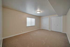 Unfurnished bedroom with light colored carpet and two closets