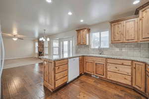 Kitchen featuring dishwasher, sink, decorative light fixtures, decorative backsplash, and a fireplace