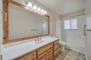 Full bathroom with vanity, toilet, and shower / bathtub combination with curtain