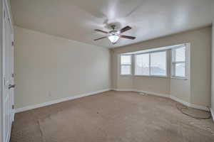 Carpeted spare room featuring ceiling fan