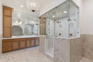 Bathroom featuring vanity, a shower with door, tile walls, and a chandelier