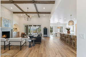 Living room featuring a fireplace, light hardwood / wood-style floors, beamed ceiling, and coffered ceiling