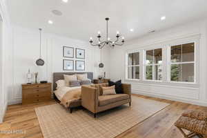 Bedroom featuring light hardwood / wood-style floors, ornamental molding, and an inviting chandelier