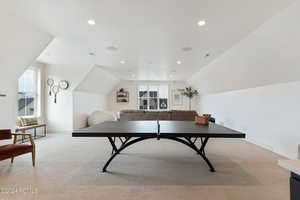 Recreation room with a wealth of natural light, light carpet, and lofted ceiling