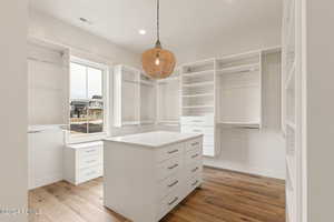 Spacious closet with light hardwood / wood-style flooring