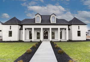 French country style house with a porch and a front lawn