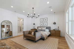 Bedroom featuring connected bathroom, crown molding, light hardwood / wood-style flooring, and a chandelier