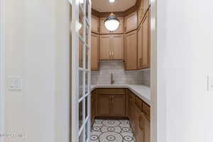 Kitchen with decorative light fixtures, sink, and backsplash