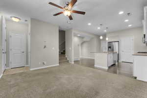 Unfurnished living room with ceiling fan and light colored carpet