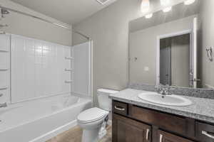 Full bathroom with tub / shower combination, vanity, a textured ceiling, tile patterned flooring, and toilet