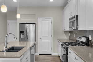 Kitchen with white cabinets, decorative light fixtures, and appliances with stainless steel finishes