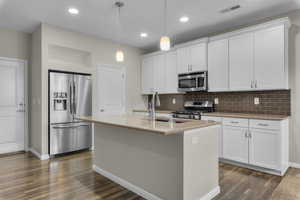 Kitchen with white cabinetry, an island with sink, and appliances with stainless steel finishes