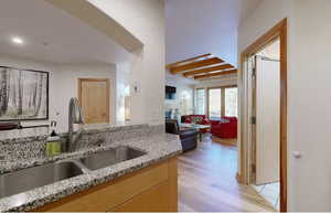 Kitchen featuring light stone counters, sink, light brown cabinets, and light wood-type flooring