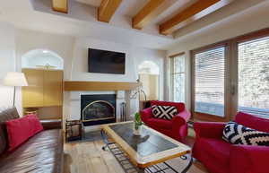 Living room featuring beam ceiling, light wood-type flooring, and plenty of natural light