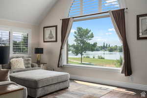 Living area featuring wood-type flooring, a water view, high vaulted ceiling, and a healthy amount of sunlight