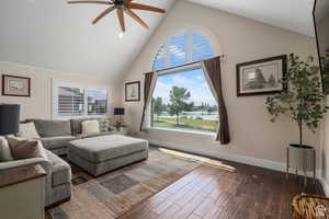 Living room featuring ceiling fan, a water view, dark hardwood / wood-style floors, and high vaulted ceiling