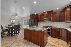 Kitchen with decorative backsplash, appliances with stainless steel finishes, french doors, light tile patterned floors, and a center island