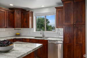 Kitchen with dishwasher, light stone countertops, sink, and tasteful backsplash