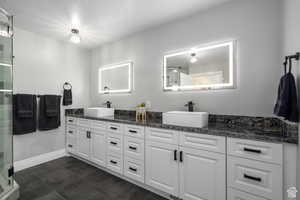 Bathroom with vanity, a shower with shower door, and a textured ceiling