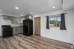 Kitchen featuring gray cabinetry, light stone counters, dark wood-type flooring, and black appliances