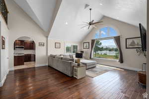 Living room with dark hardwood / wood-style floors, high vaulted ceiling, and ceiling fan