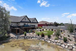 Back of house with a lawn and a deck with water view