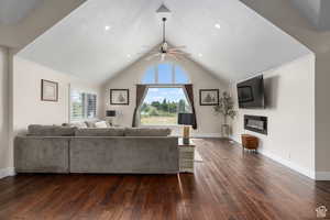 Living room featuring ceiling fan, dark hardwood / wood-style flooring, and vaulted ceiling