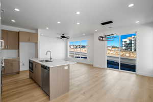 Kitchen featuring dishwasher, sink, an island with sink, decorative light fixtures, and ceiling fan with notable chandelier