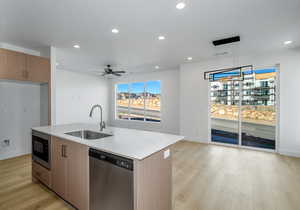 Kitchen with built in microwave, sink, hanging light fixtures, stainless steel dishwasher, and an island with sink