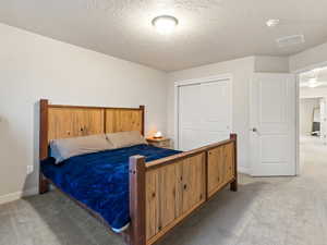 Carpeted bedroom with a textured ceiling and a closet