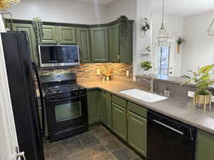 Kitchen with kitchen peninsula, decorative backsplash, sink, black appliances, and green cabinetry