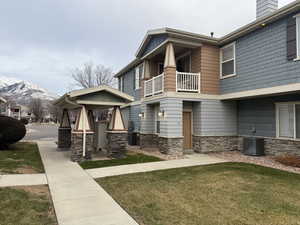 View of front of home featuring a mountain view, a balcony, a front lawn, and central AC unit