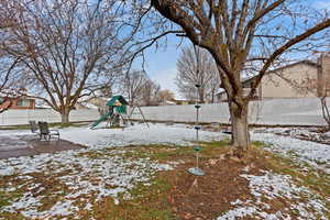 Yard layered in snow with a playground