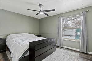 Bedroom with a textured ceiling, ceiling fan, and dark wood-type flooring