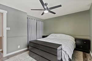 Bedroom with a textured ceiling, light hardwood / wood-style flooring, and ceiling fan