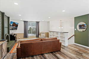 Living room with wood-type flooring, a textured ceiling, and a brick fireplace