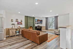 Living room with hardwood / wood-style flooring, a textured ceiling, and a brick fireplace