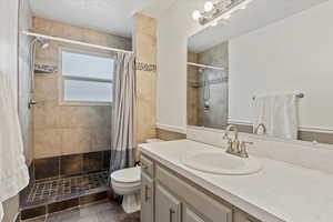 Bathroom featuring a shower with curtain, toilet, and vanity