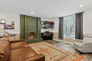 Living room featuring a brick fireplace, a healthy amount of sunlight, and hardwood / wood-style flooring