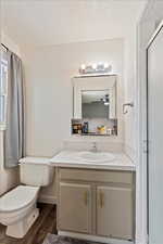 Bathroom with hardwood / wood-style floors, vanity, ceiling fan, toilet, and a shower with shower door