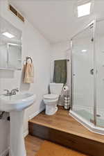 Bathroom featuring sink, walk in shower, wood-type flooring, a textured ceiling, and toilet