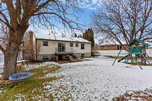 Snow covered back of property with cooling unit and a playground