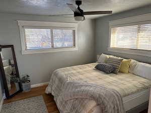 Bedroom with ceiling fan, wood-type flooring, and a textured ceiling