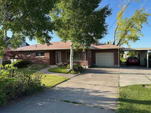 Ranch-style house featuring a garage, concrete driveway, brick siding, and an attached carport