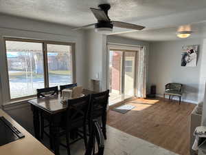 Dining area with ceiling fan, light hardwood / wood-style flooring, and a textured ceiling