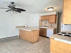 Kitchen featuring kitchen peninsula, sink, white dishwasher, and tile countertops