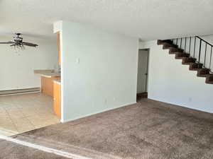 Carpeted empty room featuring a textured ceiling, a baseboard radiator, and ceiling fan