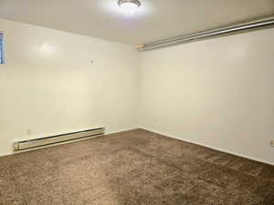 Empty room with carpet and a baseboard heating unit