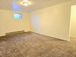 Carpeted spare room with a baseboard heating unit