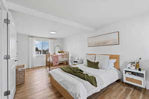 Bedroom with beamed ceiling and light wood-type flooring